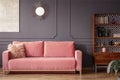 Simple, pink sofa with a fur pillow next to a wooden cupboard in Royalty Free Stock Photo