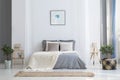 Simple poster above bed with knit blanket in bright bedroom inte