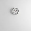 Round Wall Clock with Silver Frame and Black Numbers on a White Wall Royalty Free Stock Photo