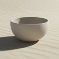 A simple round beige ceramic bowl is placed on fine sand, casting a soft shadow. The Royalty Free Stock Photo