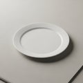 A simple, round white ceramic plate rests on a smooth, light gray surface Royalty Free Stock Photo