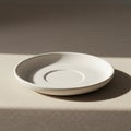 A simple, round, white ceramic saucer is placed on a textured beige surface. Sunlight Royalty Free Stock Photo