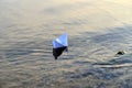 Simple small white origami paper boat floating quietly in blue clear river or sea water under bright summer sky. Royalty Free Stock Photo