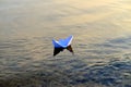 Simple small white origami paper boat floating quietly in blue clear river or sea water under bright summer sky. Royalty Free Stock Photo