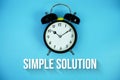 Simple Solution text and alarm clock on blue background Royalty Free Stock Photo
