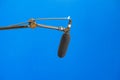A simple studio microphone on a mic arm, bluescreen, blue box chroma key professional recording studio background, nobody, object
