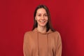 Simple studio portrait of a young wide smiling woman over red background.