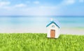 Simple style house model on green grass with space on blurred summer beach background Royalty Free Stock Photo