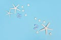 Simple summer banner with white starfish and sandals on blue background