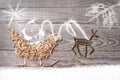 Simple symbols of Father Christmas sleigh arranged from sawdust and reindeer made from dry wooden sticks on wooden grey background Royalty Free Stock Photo