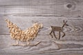 Simple symbols of Father Christmas sleigh arranged from sawdust and reindeer made from dry wooden sticks on wooden grey background Royalty Free Stock Photo