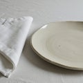 A simple tabletop setting featuring a beige, speckled, ceramic plate with a slightly Royalty Free Stock Photo