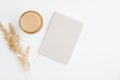 Simple trendy office desk with notebook, cup of coffee and dry reeds on white background. Minimal style feminine workspace