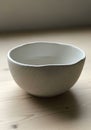 A simple, white ceramic bowl with a smooth, matte finish and subtle speckling, placed on a light Royalty Free Stock Photo