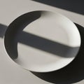 Simple white ceramic plate casting a Royalty Free Stock Photo