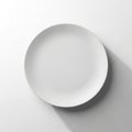 A simple white ceramic plate is centered in the image, placed against a plain light gray background. Royalty Free Stock Photo