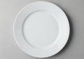 A simple white ceramic plate rests on a textured gray surface ready for a meal Royalty Free Stock Photo