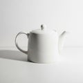 Simple White Ceramic Teapot with Lid and Handle on a White Surface kitchenware Royalty Free Stock Photo