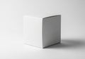 Simple white cube-shaped cardboard box on a plain, light-gray background. The box has sharp, clean Royalty Free Stock Photo