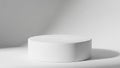 Simple white cylindrical podium on a white surface with soft shadow and light casting from the side against a white background Royalty Free Stock Photo