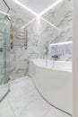 Simple white painted bathroom with lozenge shaped bath, glazed panel shower cubicle Royalty Free Stock Photo