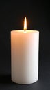 Simple white pillar candle burning with warm flame against a dark background Royalty Free Stock Photo
