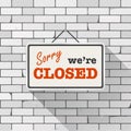 Simple white sign with text `Sorry we`re closed` hanging on a gray brick wall. Creative business interior template Royalty Free Stock Photo