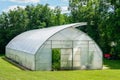 Simple wide plastic greenhouse with a open window in countryside home garden