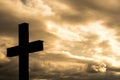 Simple wood catholic cross silhouette, dramatic orange storm clouds in the background,