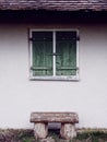 Simple wooden bench at house wall by closed window shutters Royalty Free Stock Photo
