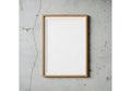 A simple wooden frame with a blank white canvas rests against a textured gray wall Royalty Free Stock Photo