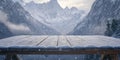 A simple wooden table covered with a light dusting of snow, with towering mountains in the Royalty Free Stock Photo
