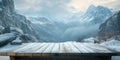 A simple wooden table covered with a light dusting of snow, with towering mountains in the Royalty Free Stock Photo