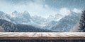 A simple wooden table covered with a light dusting of snow, with towering mountains in the Royalty Free Stock Photo