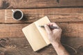 Simple work place. Wooden office desk table,  with hand writing on an empty notebook, and coffe. Morning planner concept Royalty Free Stock Photo