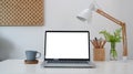 Simple workplace with laptop coffee cup, house plant and pencils holder on white table. Royalty Free Stock Photo