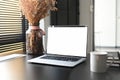 Simple workspace with blank screen laptop computer, coffee cuo, flower at studio or office.