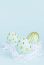 Simplicity and minimal design of easter eggs with gold in white nest on blue background, vertical.