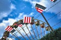 Flag with American colors with red stripes and white stars on blue background hanging next to a barbed wire fence with ferris whee