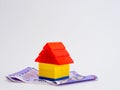 Simplistic close up shot of a lego toy house with money notes below and white background Royalty Free Stock Photo