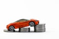 Simplistic shot of an orange toy car placed on the column of coins in automobile industry concept Royalty Free Stock Photo