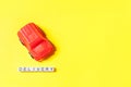 Simply design red toy car and inscription DELIVERY word isolated on yellow colorful background. Internet shopping online purchase