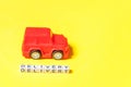 Simply design red toy car and inscription DELIVERY word isolated on yellow colorful background. Internet shopping online purchase