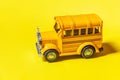 Simply design yellow classic toy car school bus isolated on yellow colorful background. Safety daily transport for kids. Back to Royalty Free Stock Photo
