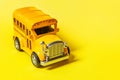 Simply design yellow classic toy car school bus isolated on yellow colorful background. Safety daily transport for kids. Back to Royalty Free Stock Photo