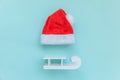 Simply minimal composition Christmas Santa Claus hat sled isolated on blue pastel colorful trendy background