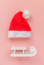 Simply minimal composition Christmas Santa Claus hat sled isolated on pink pastel colorful trendy background