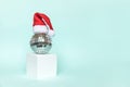 Simply minimal composition disco ball in Santa hat and cube shapes geometric form podium isolated blue pastel background. Royalty Free Stock Photo