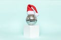 Simply minimal composition disco ball in Santa hat and cube shapes geometric form podium isolated blue pastel background Royalty Free Stock Photo