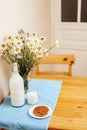 Simply stylish wooden kitchen with bottle of milk and glass on table, summer flowers camomile, healthy food moring Royalty Free Stock Photo